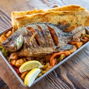Whole fried fish served over shrimp tray with garlic bread